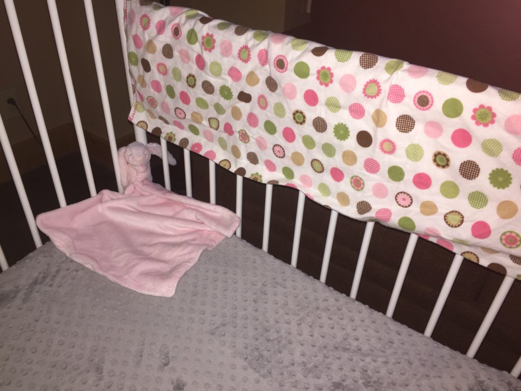 a crib sheet and comfort item in a crib provided by a hotel with a baby