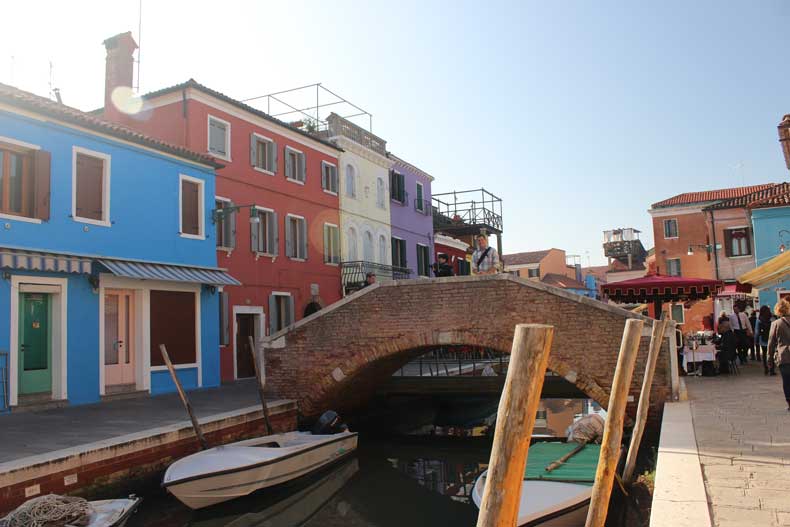 Colorful buildings and a bridge crossing a small canal in Burano, Italy