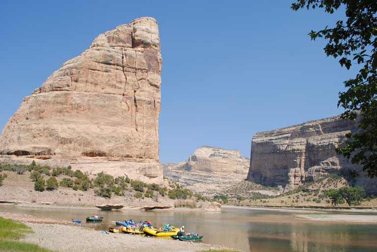 Rafts on a river with a cliff wall in the background