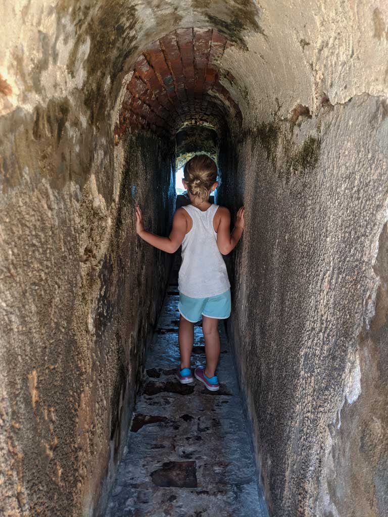 Child walking through narrow tunnel at El Morro fort in San Juan