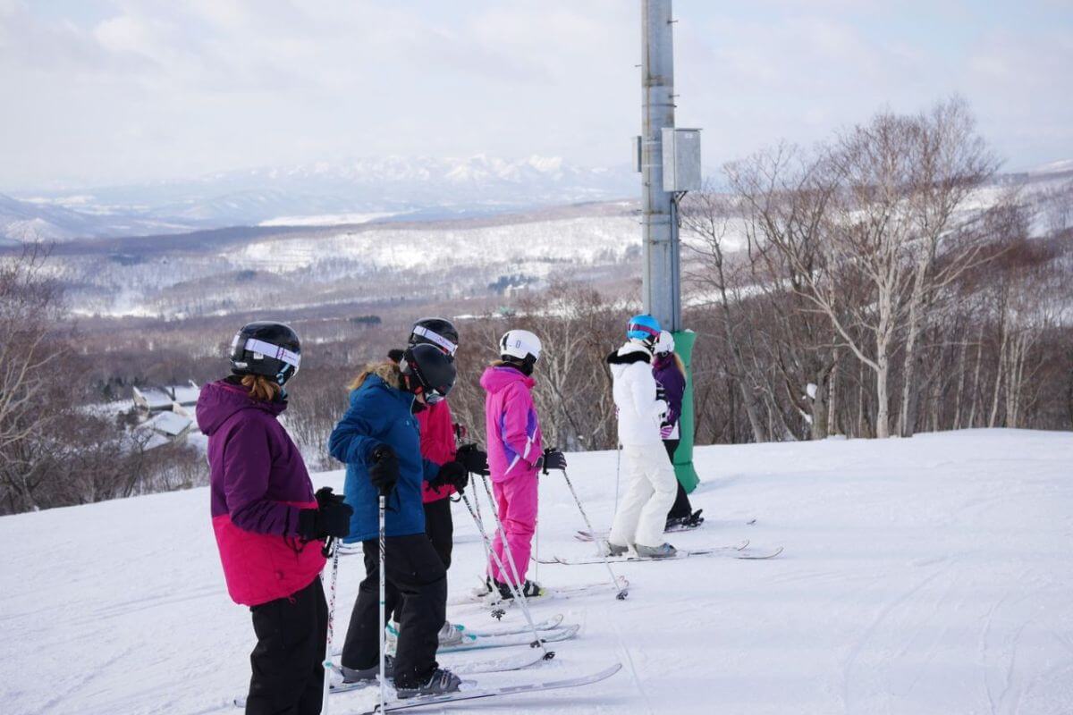 a group of people stopped at the top of a ski run in niseko japan