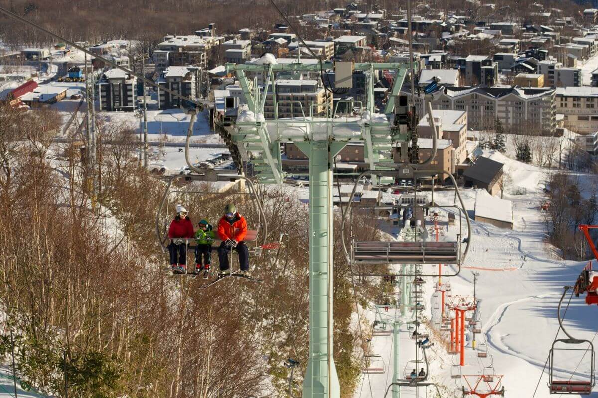 a family riding up a chair lift while skiing in Niseko