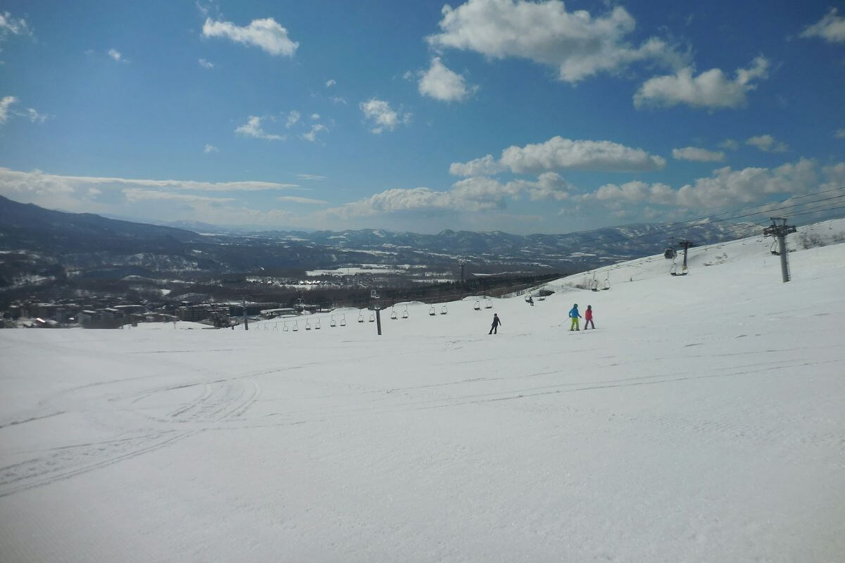 3 people skiing down a wide open ski run in Niseko