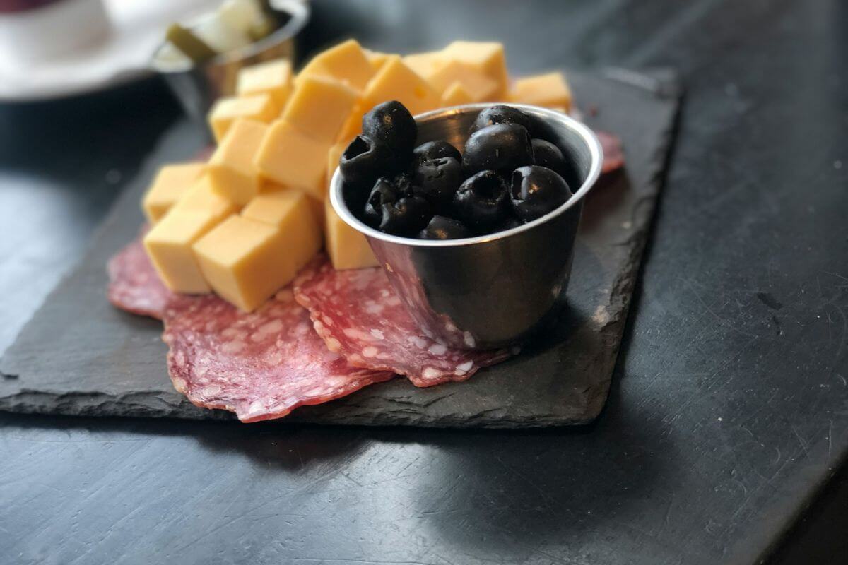 an appetizer in belgium of cheese, meat, olives, and pickles